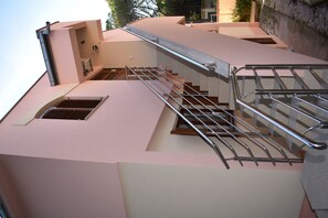 Um edifício moderno com fachada rosa, escada de metal com corrimãos e uma pequena janela.