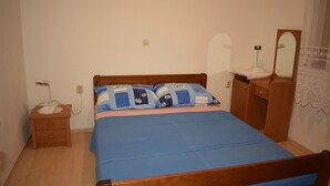 Un dormitorio con una cama de madera, una mesita de noche con una lámpara y un aparador con un espejo.