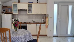 Une cuisine équipée d’un réfrigérateur, d’un four, d’un lave-vaisselle et d’une table à manger avec des chaises.