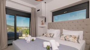 Una habitación de hotel moderna con una cama grande, dos almohadas, una mesita de noche y vistas al exterior.
