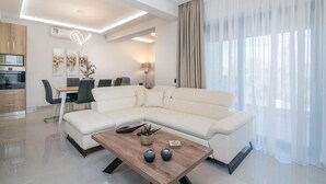 Una sala moderna con un sofá seccional, una mesa de centro de madera y un comedor con mesa y sillas.
