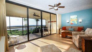 A spacious living room with a balcony overlooking a scenic view, a ceiling fan, and a sofa with patterned cushions. - Now Open, Fully remodelled and restored (Fort Myers Beach)