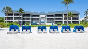A hotel with multiple floors, a beachside location, and several lounge chairs with blue covers. - Now Open, Fully remodelled and restored (Fort Myers Beach)