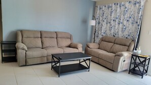 Ein Wohnzimmer mit einem beigen Sofa, einem schwarzen Couchtisch und einem Beistelltisch mit einer Lampe.