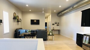 A modern living room with a sofa, dining table, and kitchen area. - Is This Heaven Downtown Dyersville Apartment (Dyersville)