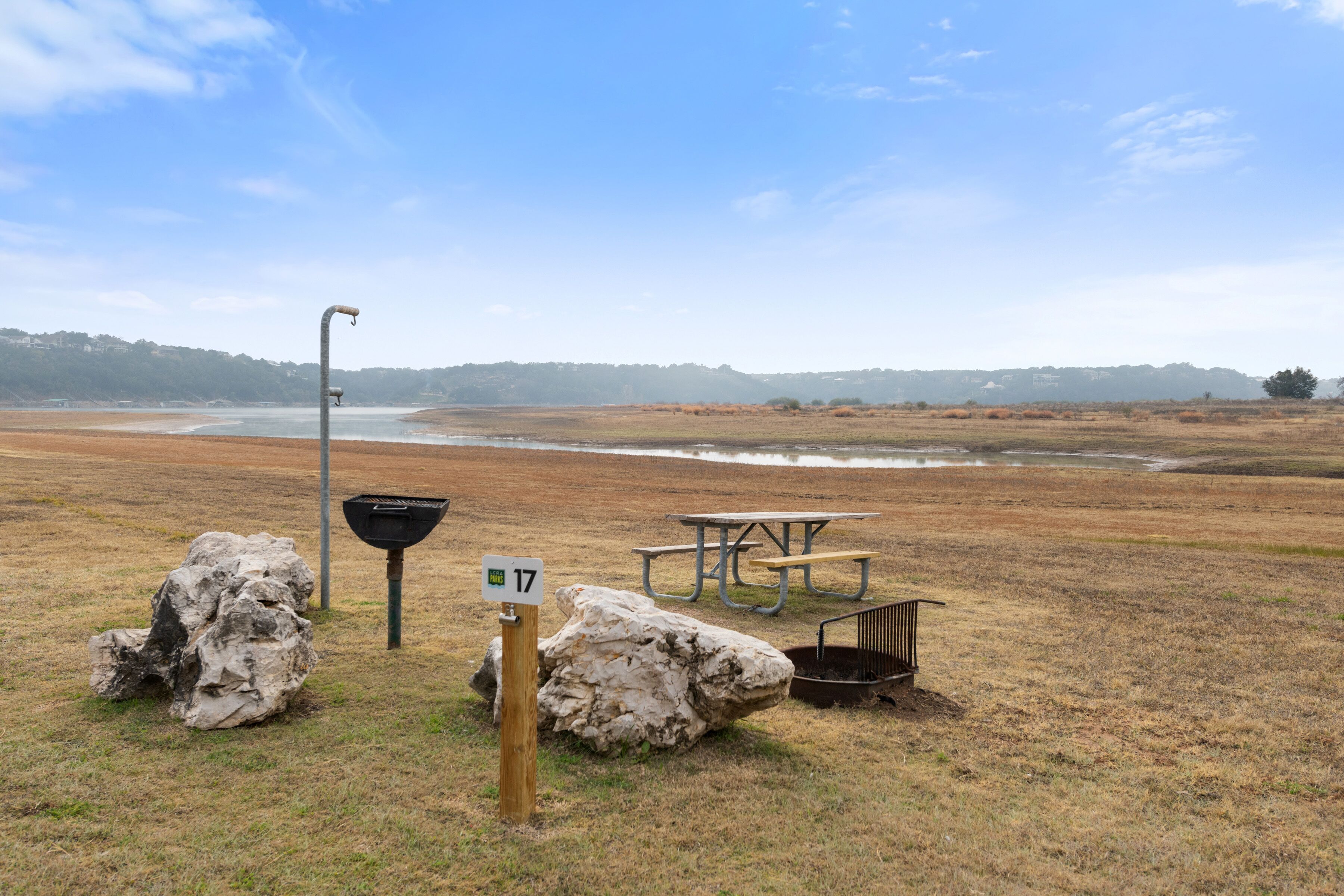 A picnic area with a bench, a trash bin, and a sign indicating the location.