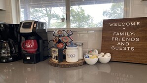 A coffee station with a coffee maker, a mug, a coffee dispenser, and a sign welcoming family, friends, and guests. - Hillside Paradise near Hidden Falls! Clean 3/1.5, Expansive views (Marble Falls)