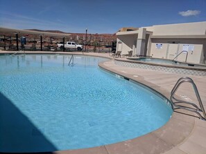 A swimming pool with a metal ladder, a covered seating area, and a white vehicle parked nearby. - Suite With A View | Private Hot Tub (Washington)
