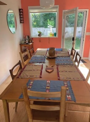 Un coin repas avec une table en bois, des chaises et une fenêtre donnant sur l’extérieur.