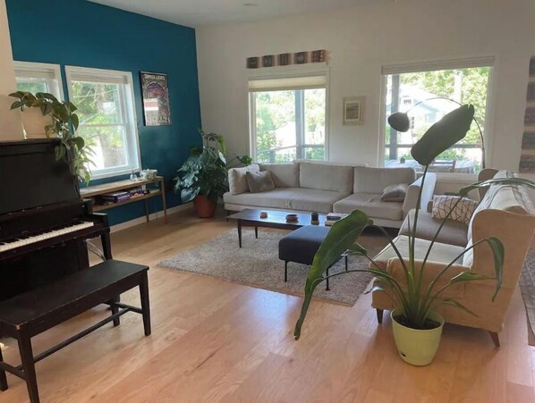 Un salon avec un piano, un canapé, une table basse et plusieurs plantes en pot.