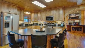 A spacious kitchen with wooden cabinets, a central island with bar stools, and modern appliances.