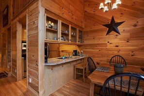 A wooden cabin interior with a kitchen area, dining table, and chairs.