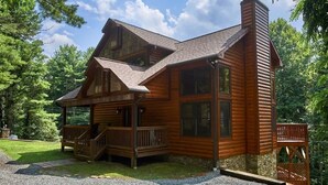 Eine Blockhütte mit Veranda, Schornstein und Natursteinfundament.