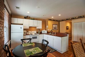 Una cocina compacta con armarios blancos, una isla central y una mesa de comedor con sillas.