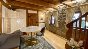 A wooden interior with a stone wall, a wooden staircase, a round table with chairs, and a decorative vase. - My mini house | 2 rooms | Smart TV | Stone & wood (Karlsruhe)