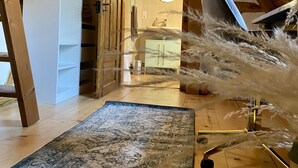 A room with a wooden ceiling, a mirror, a chair, a rug, and a wooden floor. - My mini house | 2 rooms | Smart TV | Stone & wood (Karlsruhe)