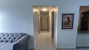 Un saló modern amb un sofà gris, una catifa blava i un passadís que condueix a una altra habitació.