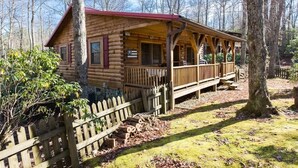Eine Blockhütte mit Veranda und überdachter Terrasse, umgeben von Bäumen.