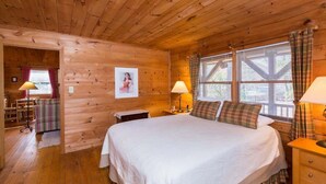 Ein Schlafzimmer einer Holzhütte mit einem großen Bett, zwei Nachttischen und Karottenvorhängen.