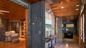 A spacious room with a stone accent wall, a wooden ceiling, and a seating area with a sofa and ottoman.