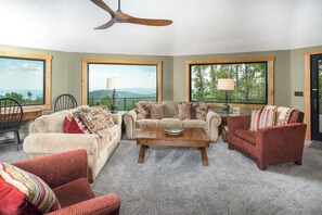A living room with a sofa set, armchairs, a coffee table, and a ceiling fan.