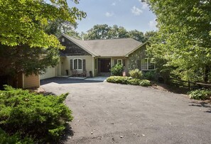 A single-story house with a stone facade, a front porch, and a driveway leading to the entrance.