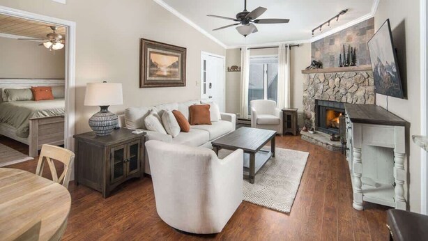 A spacious living room with a fireplace, a ceiling fan, and a dining area with a table and chairs. - Bearway to Heaven - 2BR/2BA Condo, Downtown BR (Blowing Rock)