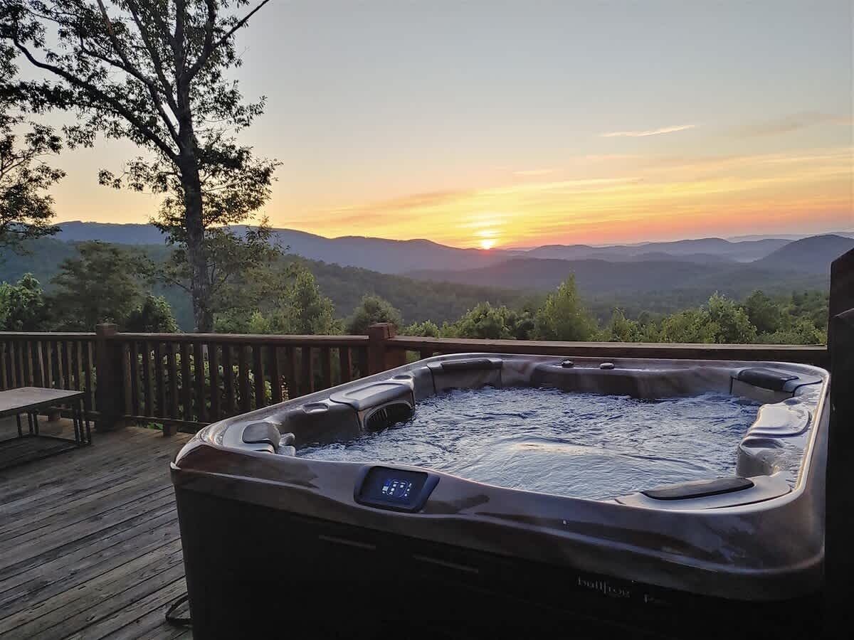 Una vasca idromassaggio su un pontile di legno con vista sul tramonto.