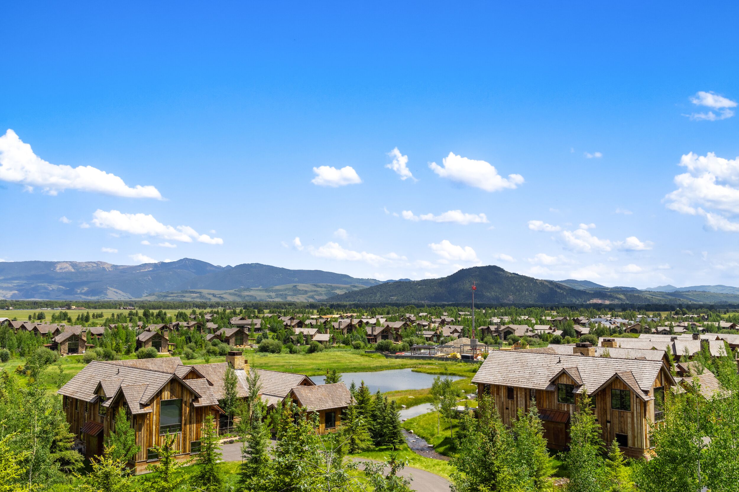Un complexe hôtelier doté de chalets en bois, d’un lac et de montagnes en toile de fond.