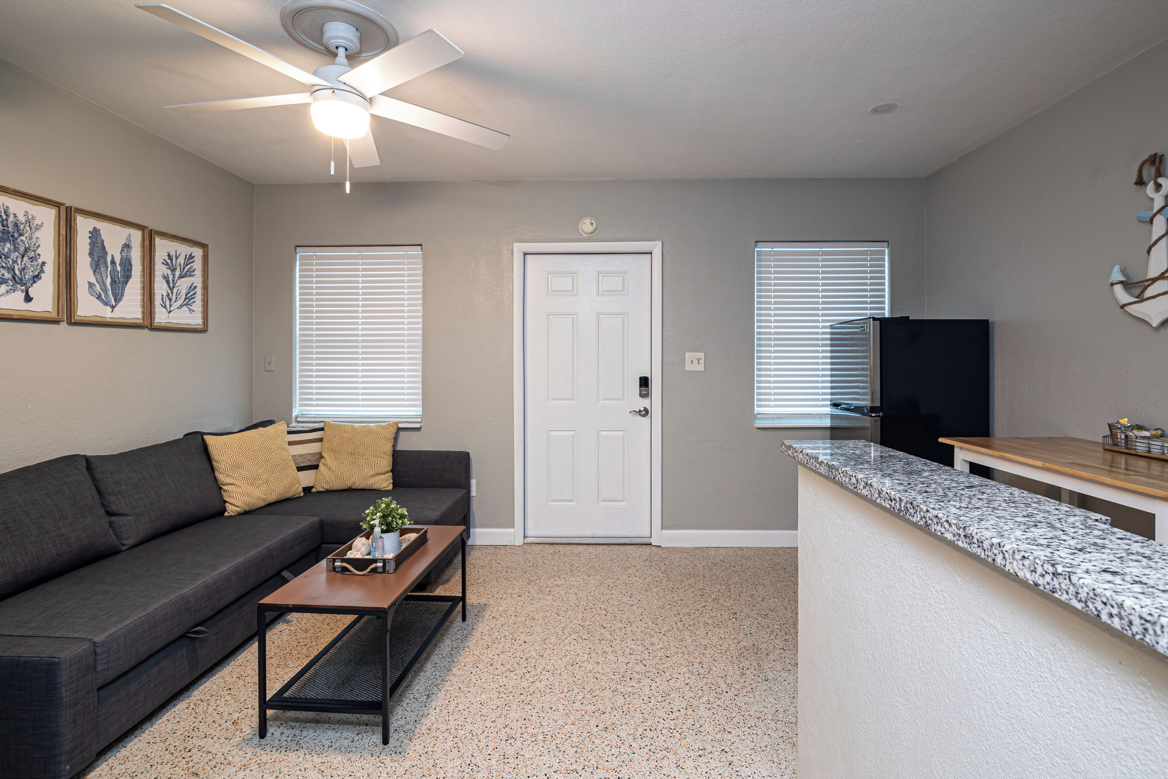 A living room with a dark grey sofa, a wooden coffee table, and a ceiling fan.