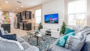 Een moderne woonkamer met een bank, een glazen salontafel en een flatscreen televisie aan de muur.
