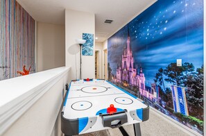 A room with a pool table, a mural of a castle, and a wall with vertical stripes.