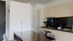 Eine moderne Küche mit Backofen, Spüle und Arbeitsplatte. An der Wand ist ein Telefon angebracht und ein Handtuchhalter vorhanden.