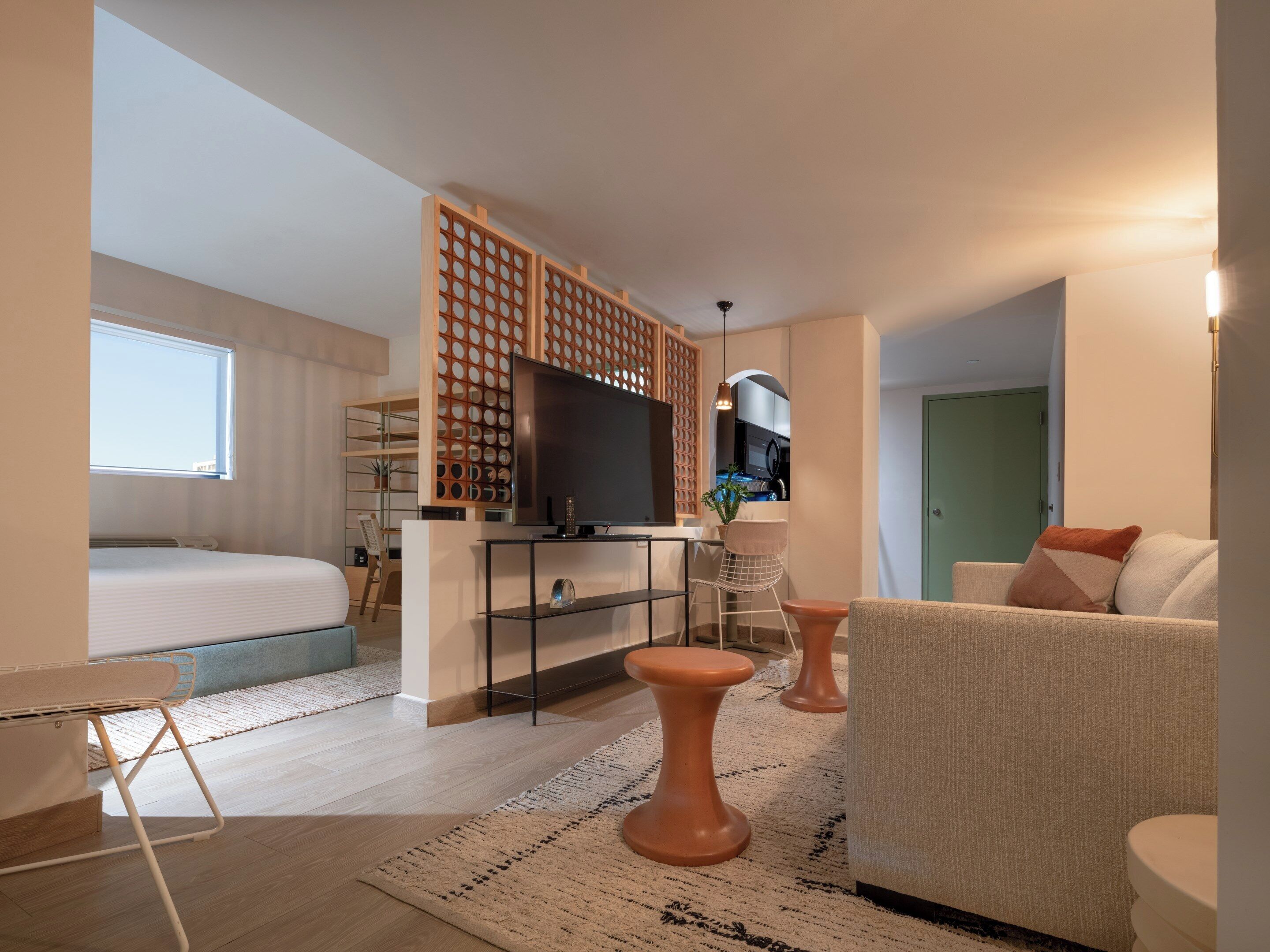 Una habitación de hotel moderna con cama, escritorio, televisor, sofá y zona de comedor.
