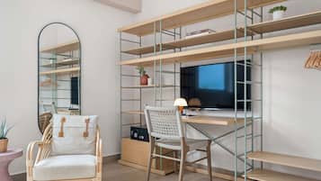Un espace de travail moderne comprenant un bureau, une chaise, des étagères et un téléviseur.
