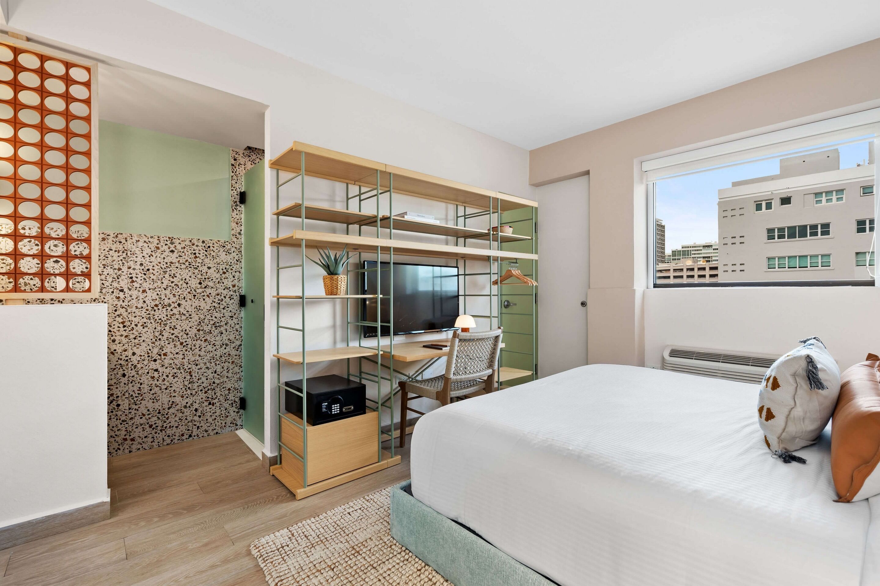 Une chambre à coucher avec un lit, un bureau avec un ordinateur, une chaise et un téléviseur.