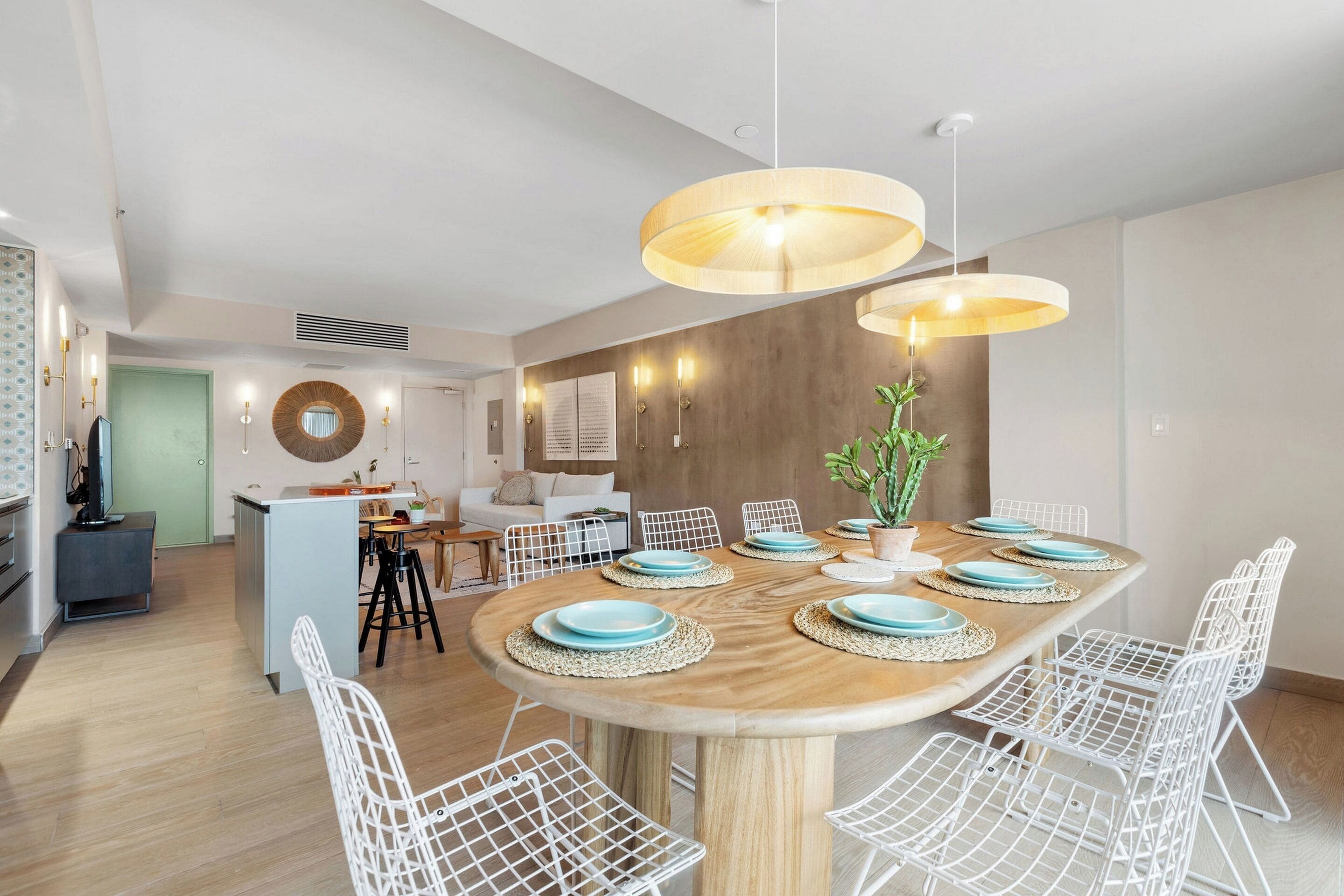 A modern dining area with a wooden table, white wire chairs, and blue plates.