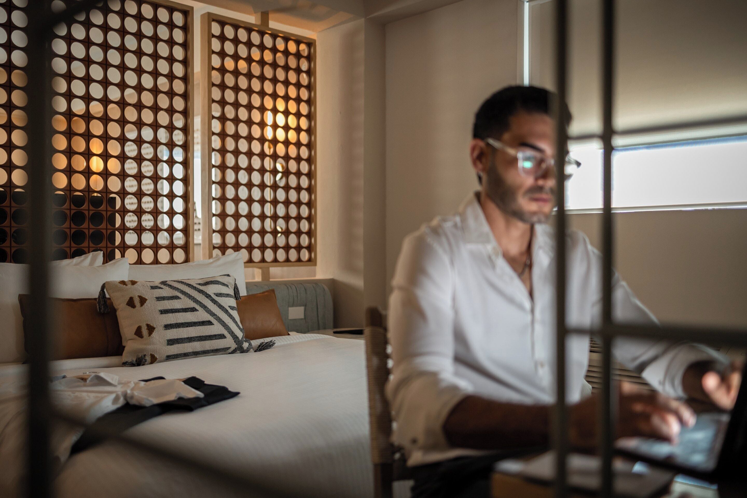 A hotel room with a bed, a desk, and a laptop.