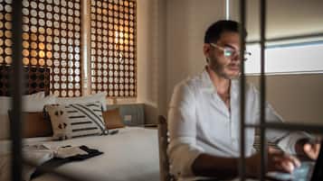 A hotel room with a bed, a desk, and a laptop.