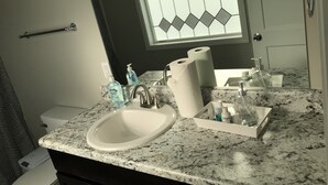 Une salle de bain équipée d’un lavabo, d’un miroir et d’articles de toilette.