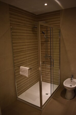 A modern bathroom with a glass-enclosed shower, a white sink, and a towel rack.