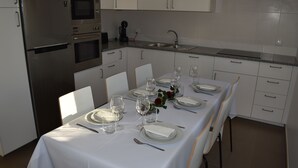 A dining area with a table set for four, equipped with plates, glasses, and cutlery. - Casa do sapateiro (Ferrel)