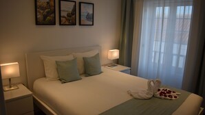 A neatly made bed with pillows, a bedside lamp, and a towel on the bed. - Casa do sapateiro (Ferrel)
