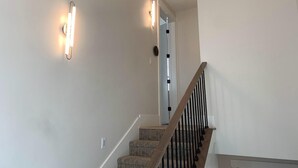 Una escalera con barandillas de madera y un rellano alfombrado.