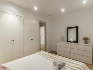 A bedroom with a bed, a dresser, a mirror, and a wardrobe.