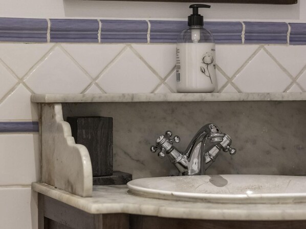 A bathroom sink with a marble countertop and a faucet.