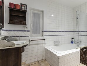 A bathroom with a sink, mirror, window, shower, and a bathtub.