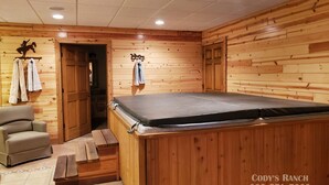 Una habitación de madera con una camilla de masaje, una silla y una puerta que da a otra estancia.