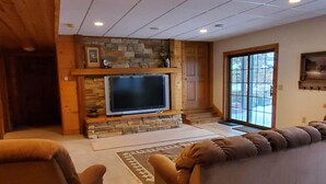 Una sala de estar acogedora con chimenea de piedra, televisor de pantalla plana y asientos cómodos.