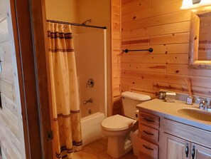 Un baño con pared de madera, una bañera, un inodoro y un lavabo con espejo.